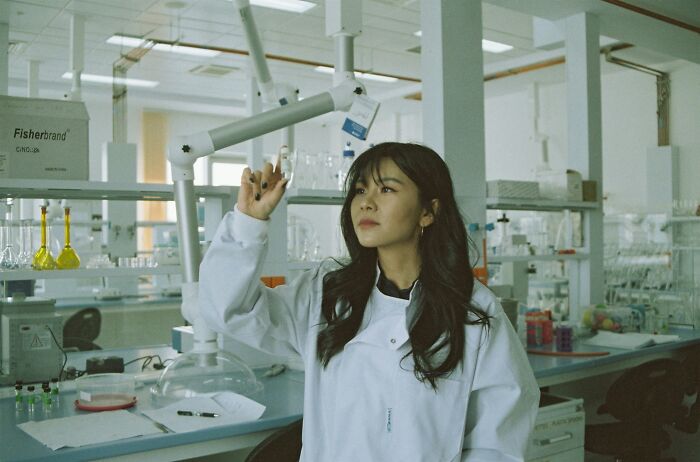 Woman in white lab coat working in a modern laboratory, symbolizing pressing issues plaguing America at the moment.