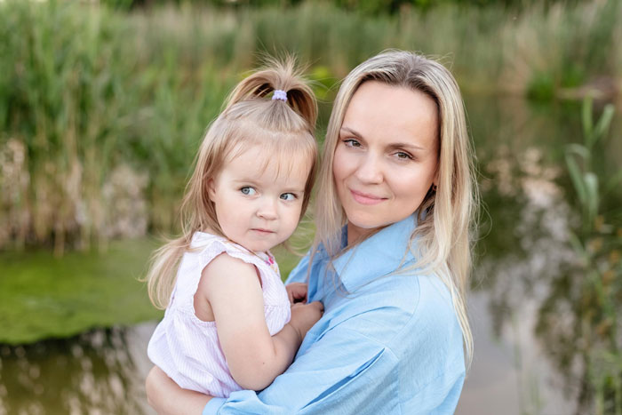 Woman holding toddler outdoors looking concerned about MIL not changing kid's diaper, showing parenting and family care issues.