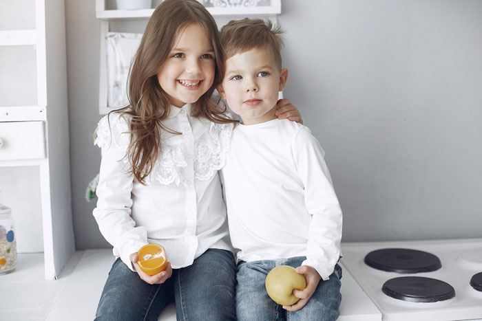 Two children sitting together, smiling, representing a family with a disabled son affecting their normal life.