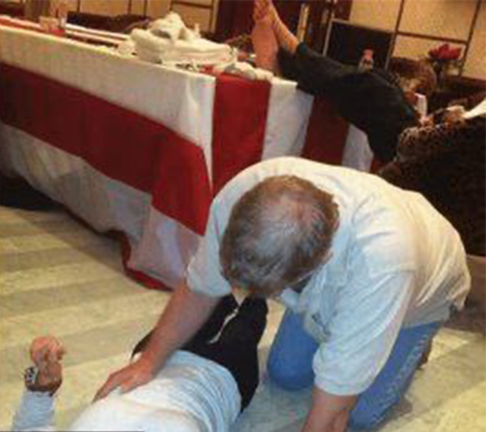 Disturbing images related to Prince Andrew show a man lying on the floor with another person leaning over him indoors.