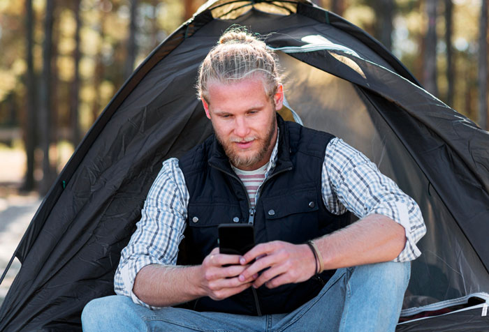 Man sitting outside a tent using his phone, hinting at a camping trip with his brother but the brother was at home.