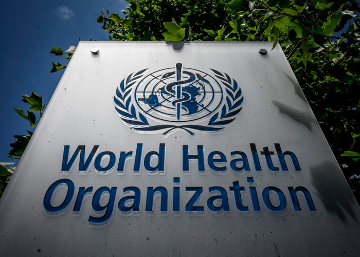 World Health Organization sign outdoors with foliage, related to doctor warning on incurable virus and airport restrictions.