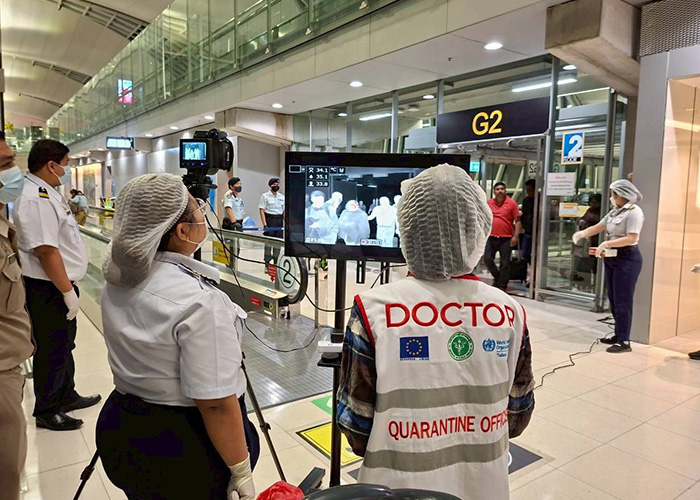 Airport quarantine officer and staff using thermal scanner during virus outbreak with COVID-style restrictions in place.