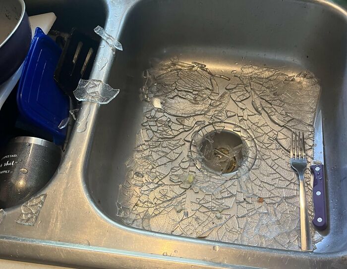 Broken glass scattered in a kitchen sink alongside a fork, illustrating an unfortunate and expensive fail.