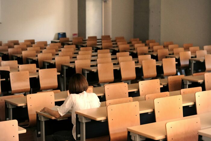 Student sitting alone in an empty classroom, illustrating the weirdest teacher behavior witnessed in class experiences.