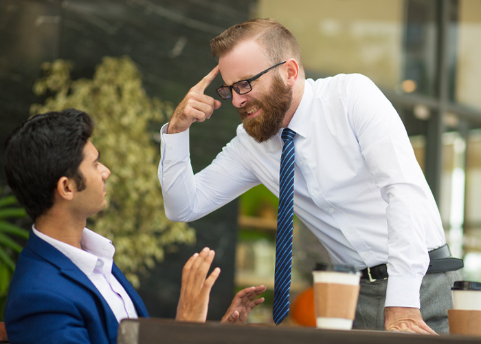 Two men in a tense office discussion, highlighting Dutch worker giving annoyed American boss a reality check after logging off at 5PM.