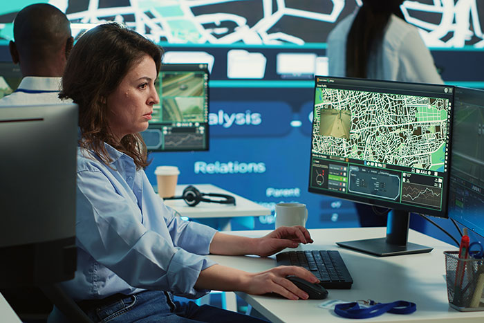 Emergency dispatcher at workstation analyzing maps and data, illustrating tips for calling 911 efficiently