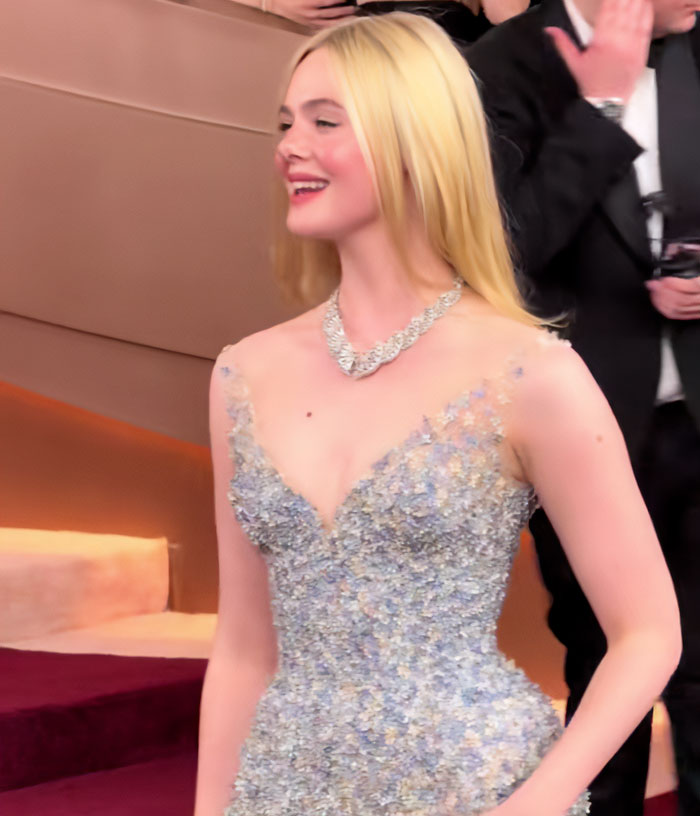 Elle Fanning standing tall in a shimmering gown, highlighting stunning height at a glamorous star-studded event.