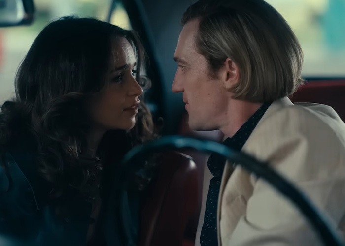 Emilia Clarke filming an intense intimate scene with a male co-star inside a car, showing emotional connection.