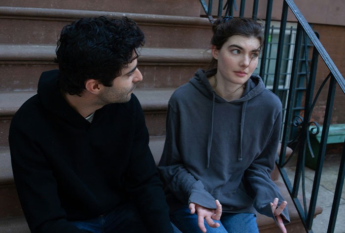 Woman and man sitting on stairs, woman looking troubled while discussing engagement and family relationships.