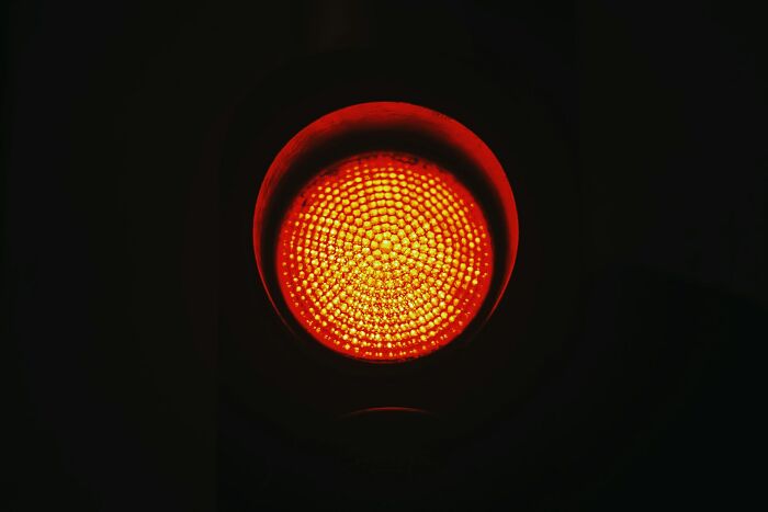 Red traffic light glowing in darkness symbolizing daily dangers you might not realize you're exposed to.