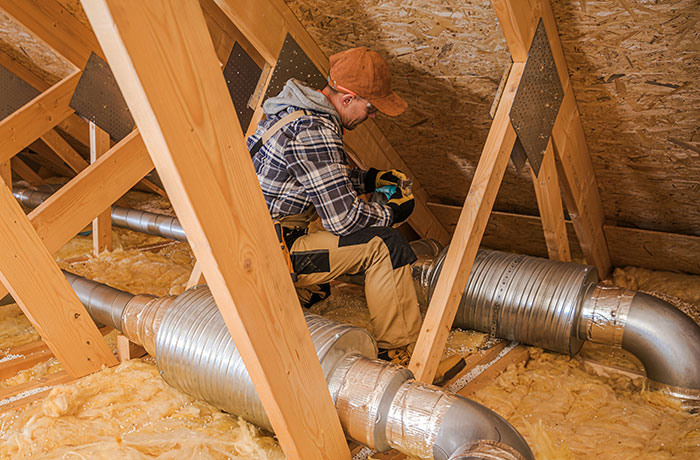 Man in workwear inspecting ventilation ducts in attic, illustrating moments when the expert was wrong unexpectedly