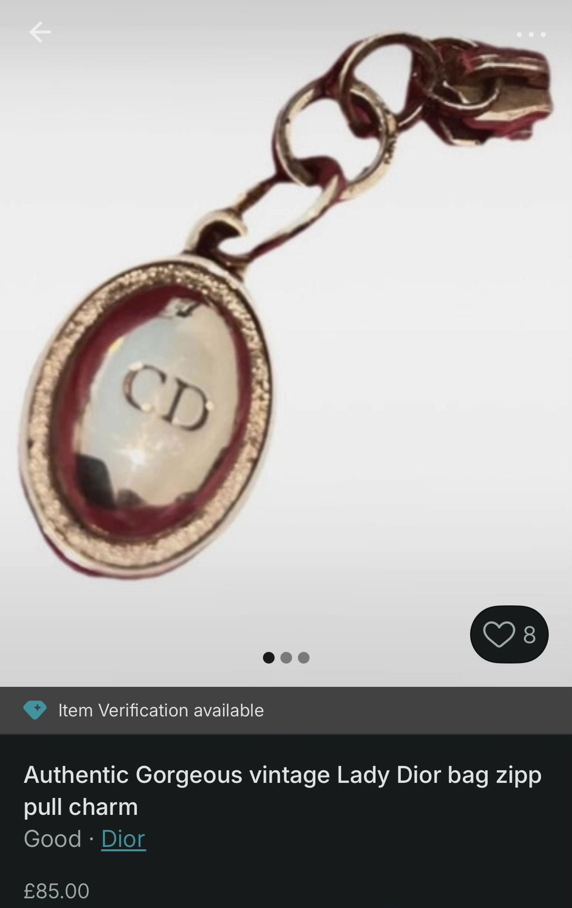 Close-up of an authentic vintage Dior handbag zipper pull charm with CD logo in gold-tone metal.