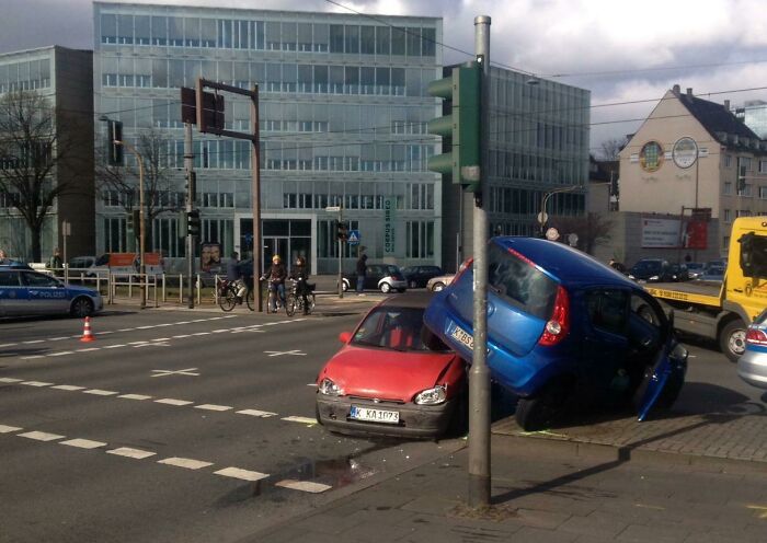 Two cars involved in a confusing accident at an urban intersection, creating a funny and puzzling scene.
