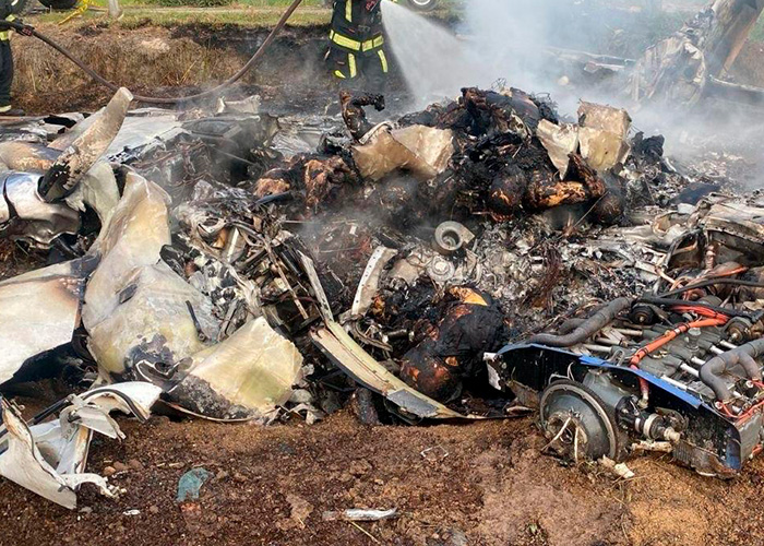 Wreckage of a plane crash site with firefighters extinguishing smoke, related to famous singer's tragic accident. Wreckage of a plane crash site with firefighters extinguishing smoke, related to famous singer's tragic accident.