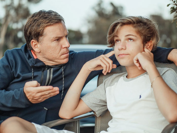Father intensely talking to his teenage son who looks disengaged, illustrating challenges in dad and children relationships. Father intensely talking to his teenage son who looks disengaged, illustrating challenges in dad and children relationships.