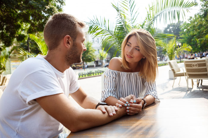 Couple having a tense conversation while holding hands outdoors, highlighting therapy battle and relationship boundaries.