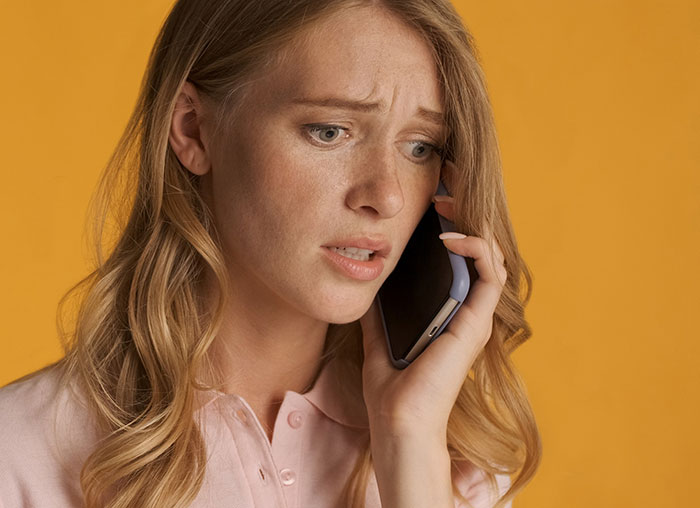 Distressed woman on phone reacting after boyfriend breaks off engagement