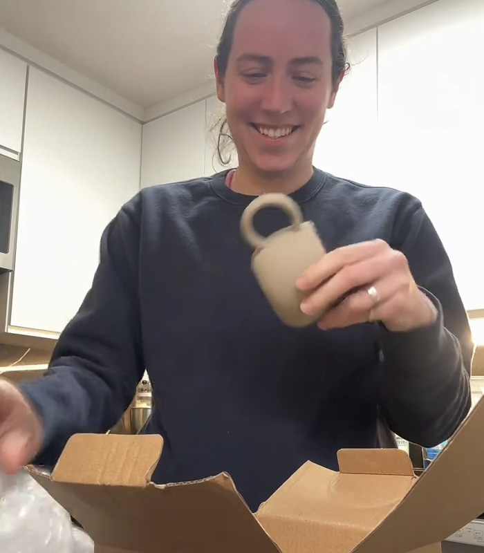 Woman smiling while holding a mug gift from fiancé, sparking a huge relationship debate online. Woman smiling while holding a mug gift from fiancé, sparking a huge relationship debate online.