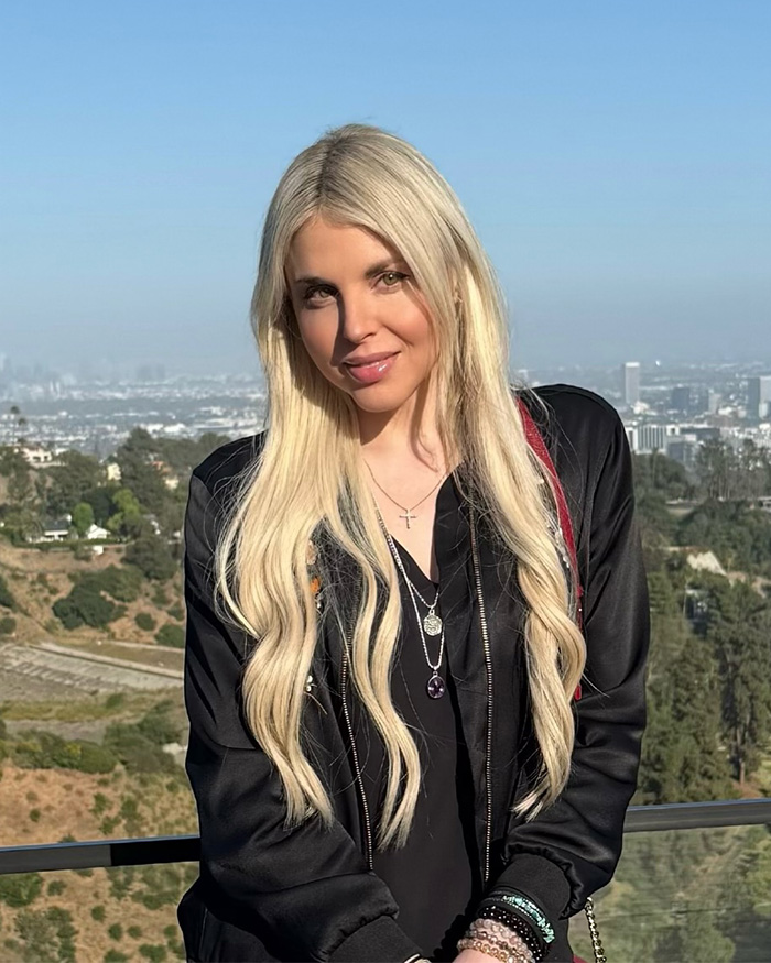 Firerose posing outdoors with long blonde hair and layered necklaces supporting disturbing accusations against Billy Ray Cyrus.