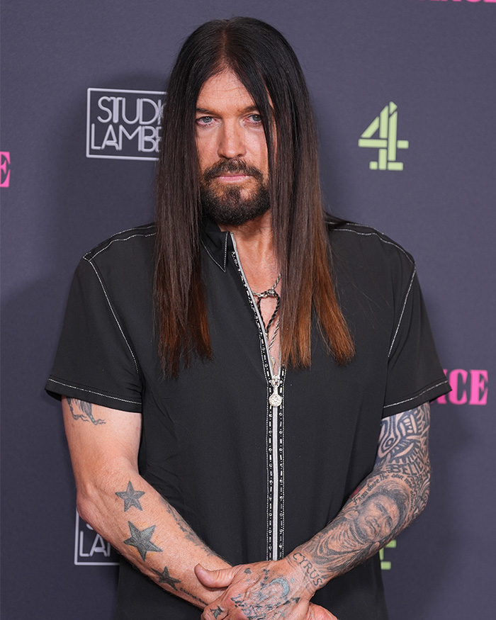 Man with long hair and tattoos posing at an event related to Firerose drops bombshell audio accusation against Billy Ray Cyrus