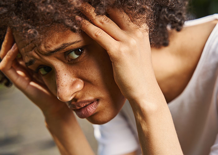 Young woman worried and stressed, holding her head, symbolizing emotional distress from fabricated cheating evidence.