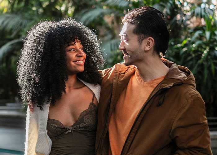 Woman with curly hair smiling at man in a brown jacket, illustrating fabricated cheating evidence and friendship betrayal concept.
