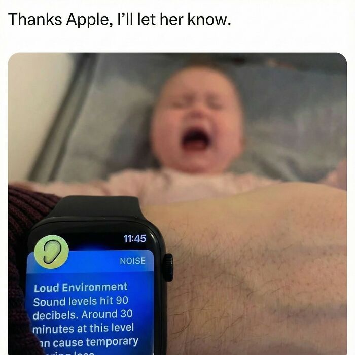 Smartwatch shows loud noise warning as baby cries loudly in background, a funny meme highlighting randomness and everyday life.