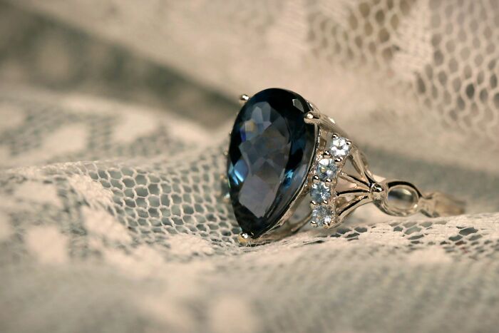 Close-up of an elegant ring with a dark gemstone and small diamonds, symbolizing moments so ridiculous they seemed like pranks.