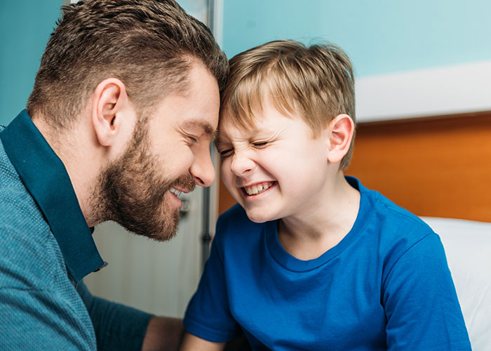 Man and young boy smiling and touching foreheads in a playful moment highlighting a woman's award winning act in court.