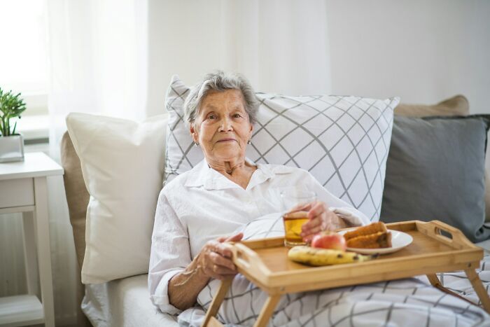 Elderly woman with a really bad prognosis resting in bed with a tray of food and drink, representing unexplainable medical events.