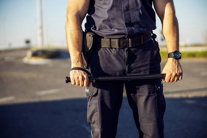 Correctional officer holding a baton standing outdoors, illustrating truths behind misconceptions about life in prison.