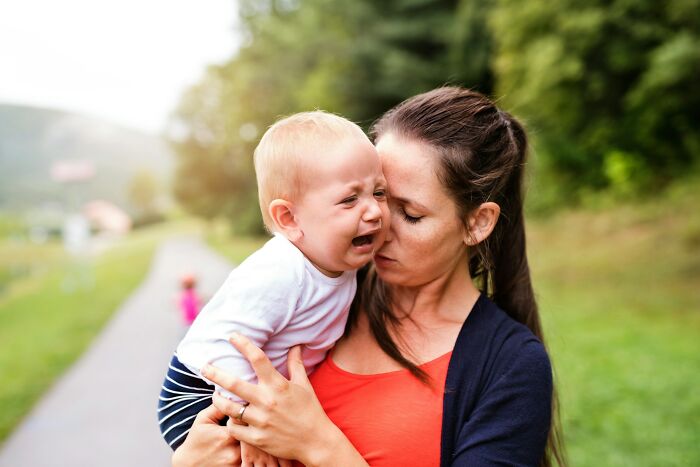 Woman comforting a crying baby outdoors, symbolizing emotional moments former cult members reveal when they knew they were in a cult