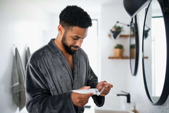 Man in a dark robe measuring medication in a modern bathroom, highlighting daily dangers you might not realize.