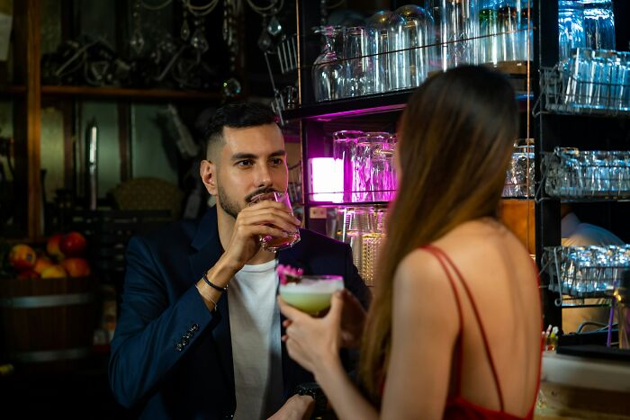 Man and woman having drinks at a bar, illustrating things women do to feel safer while living alone.