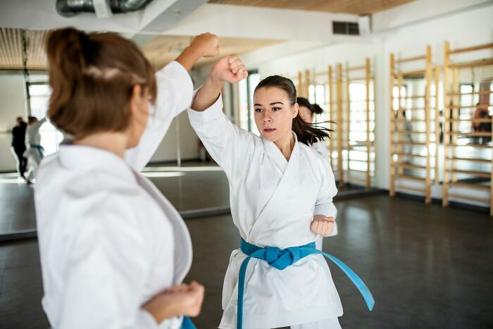 Woman practicing self-defense martial arts indoors, demonstrating techniques to feel safer while living alone.