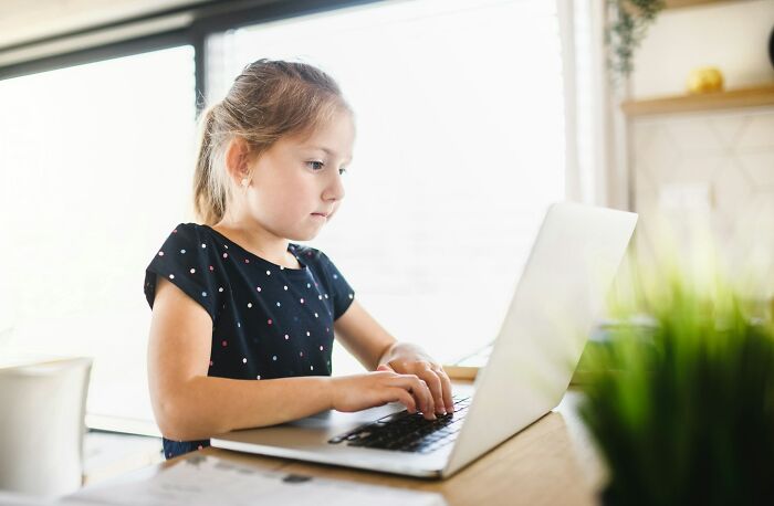 Young girl focused on typing on laptop at home, illustrating moments when people were surprised or creeped out by intelligence.