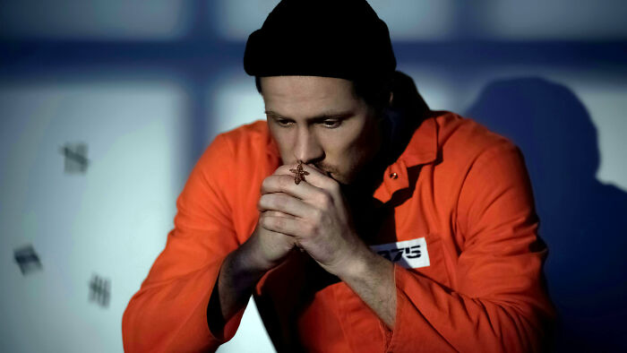 Man in orange prison uniform sitting and reflecting, illustrating misconceptions about life in prison.