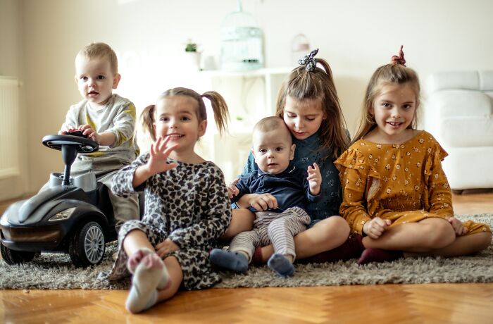 Five young children sitting together on a rug in a bright room, illustrating DNA test family surprises and connections.