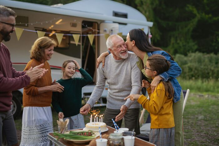 Family celebrating a birthday outdoors, showcasing normal practices in Europe that the US may find weird.