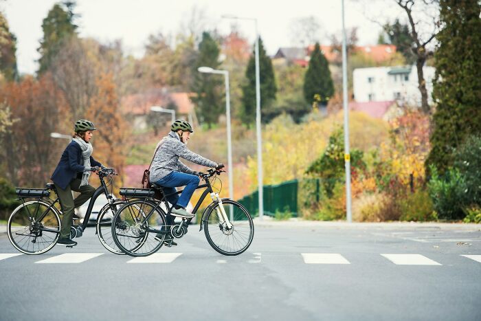 Two people wearing helmets riding bikes across a street highlighting daily dangers you might not realize.