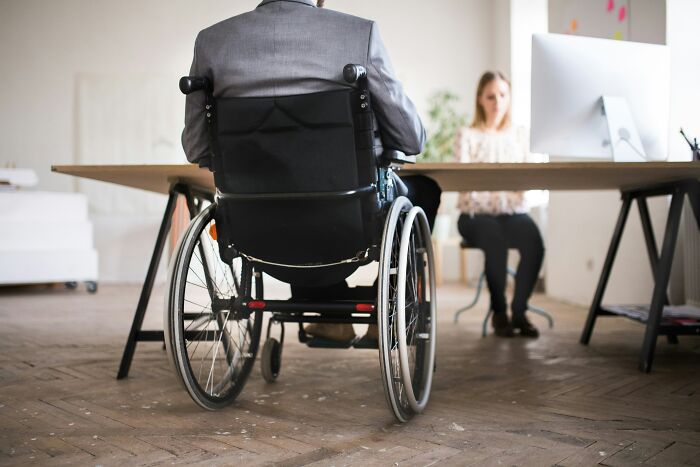 Man in wheelchair meeting with colleague in an office highlighting pressing issues plaguing America at the moment.