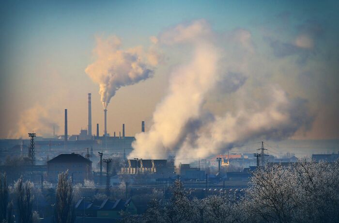 Industrial factories in America emitting large smoke plumes, highlighting pressing pollution and environmental issues.