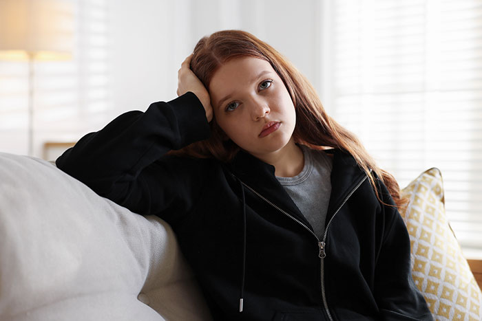 Teen girl with red hair looking thoughtful and pensive, representing gifted kids reflecting on their potential.