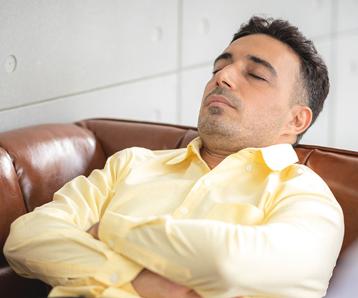 Man in a yellow shirt resting on a couch, appearing relaxed and contemplative about gifted kids and their potential.