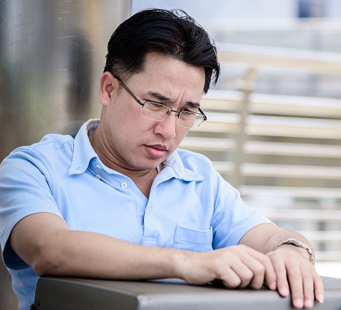 Man wearing glasses and a blue shirt looking thoughtful, representing gifted kids with potential reflecting on success.
