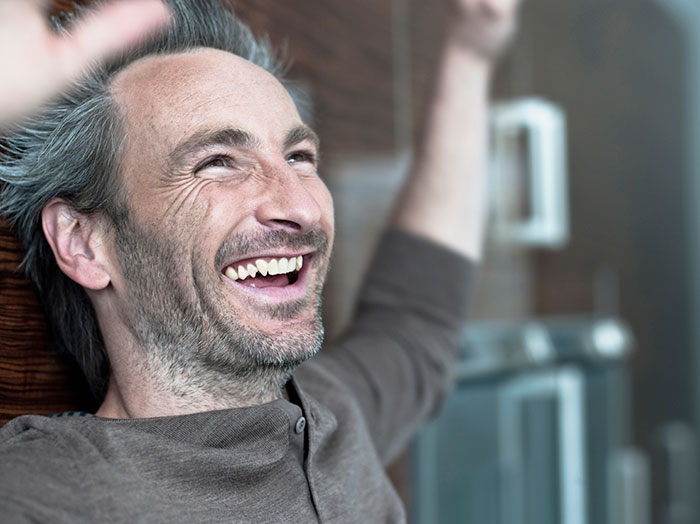 Middle-aged man smiling and raising arms, reflecting on gifted kids who had potential to do great things shared.