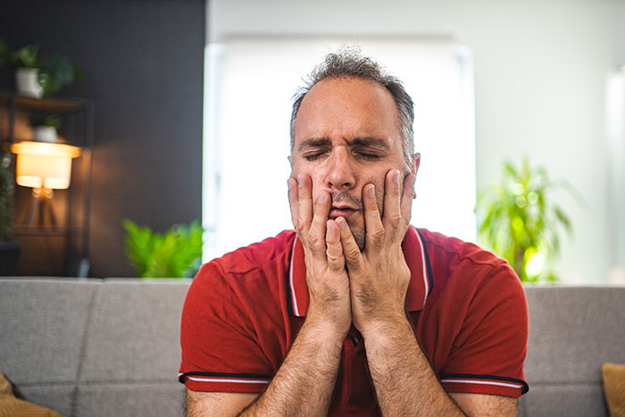 Man in a red polo shirt sitting on a couch with a stressed expression, reflecting on gifted kids and potential.