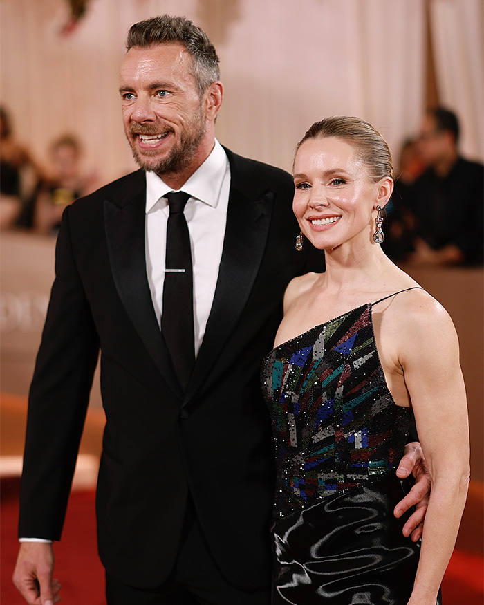 A well-dressed man and woman posing on the red carpet at the 2026 Golden Globes amid chaos and arrogant stars.