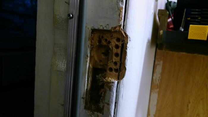 Close-up of a badly damaged door frame showing a failed DIY repair with rough and uneven woodwork.